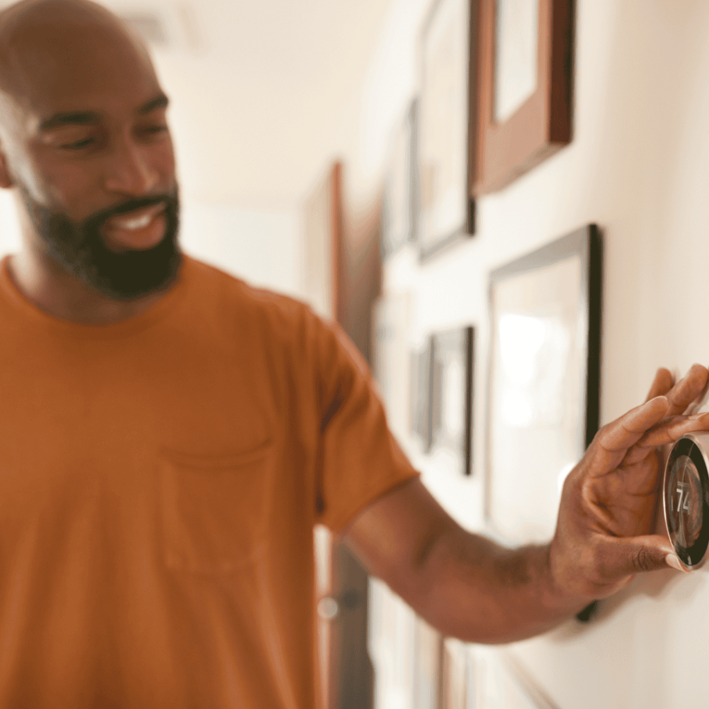 man setting thermostat in order to lower heating costs during winter